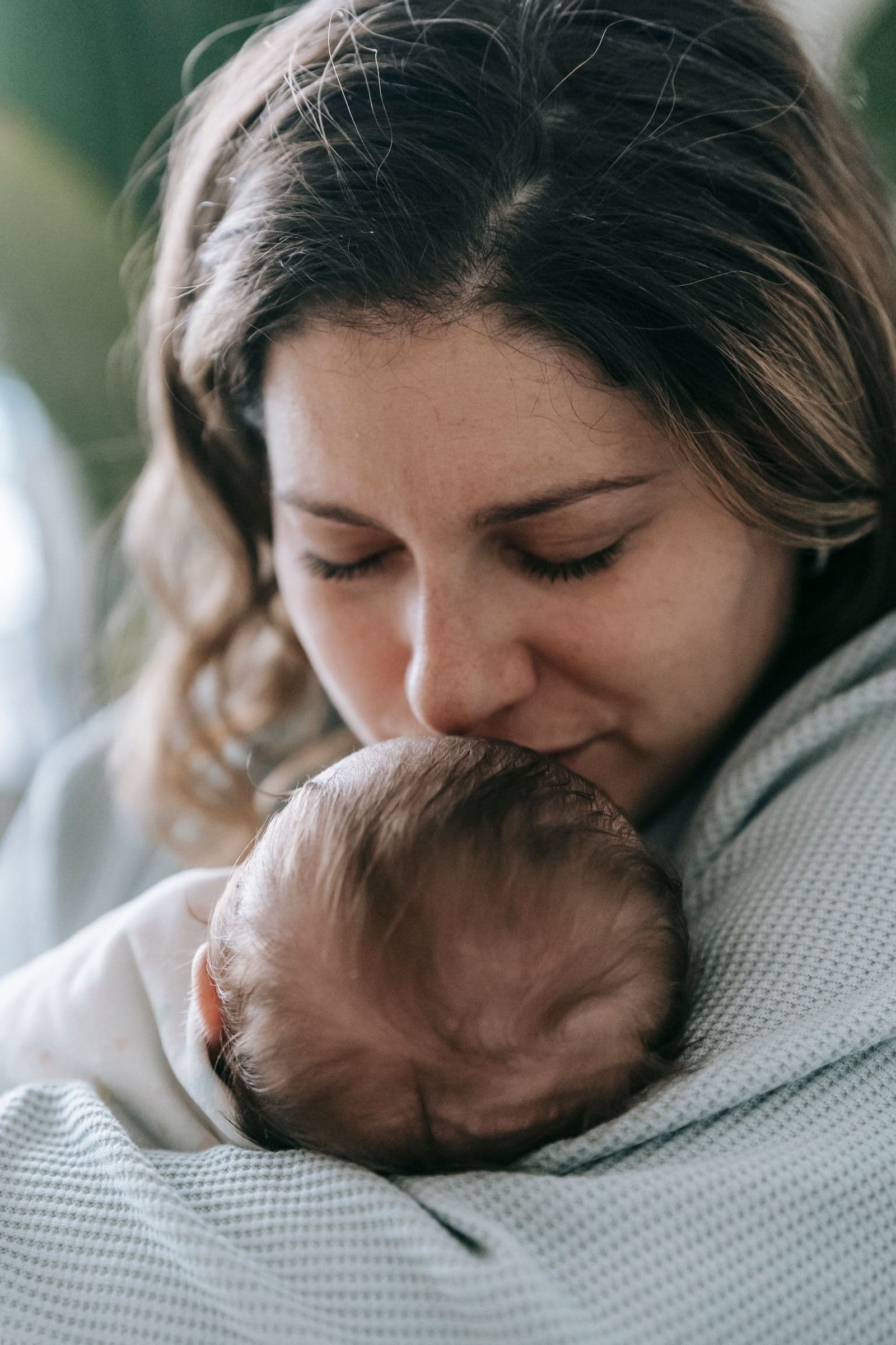 A parent holding a sleeping newborn against their shoulder